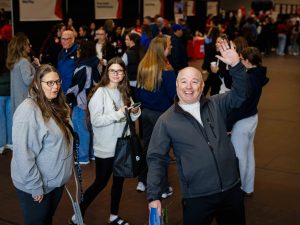 Visitors smile and wave while exploring the event’s information fair.