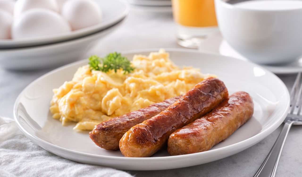 A plate with scrambled eggs and sausage.