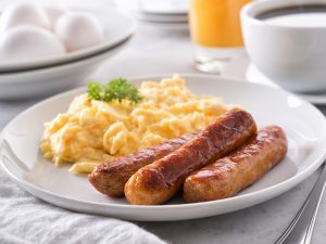A plate with scrambled eggs and sausage.