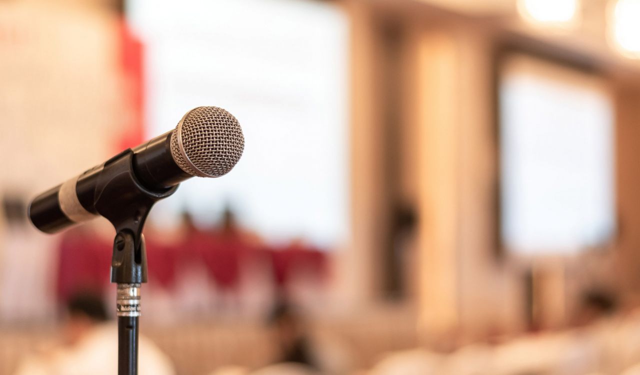 Close-up of a microphone against an out-of-focus conference room.