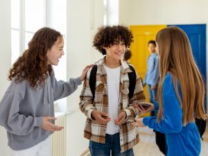 A group of teenagers stand together in a hallway talking.