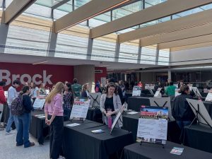 People walk around tables at an information fair.