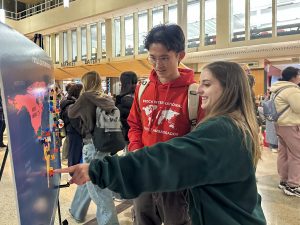 Two university students look at a map during a large event.