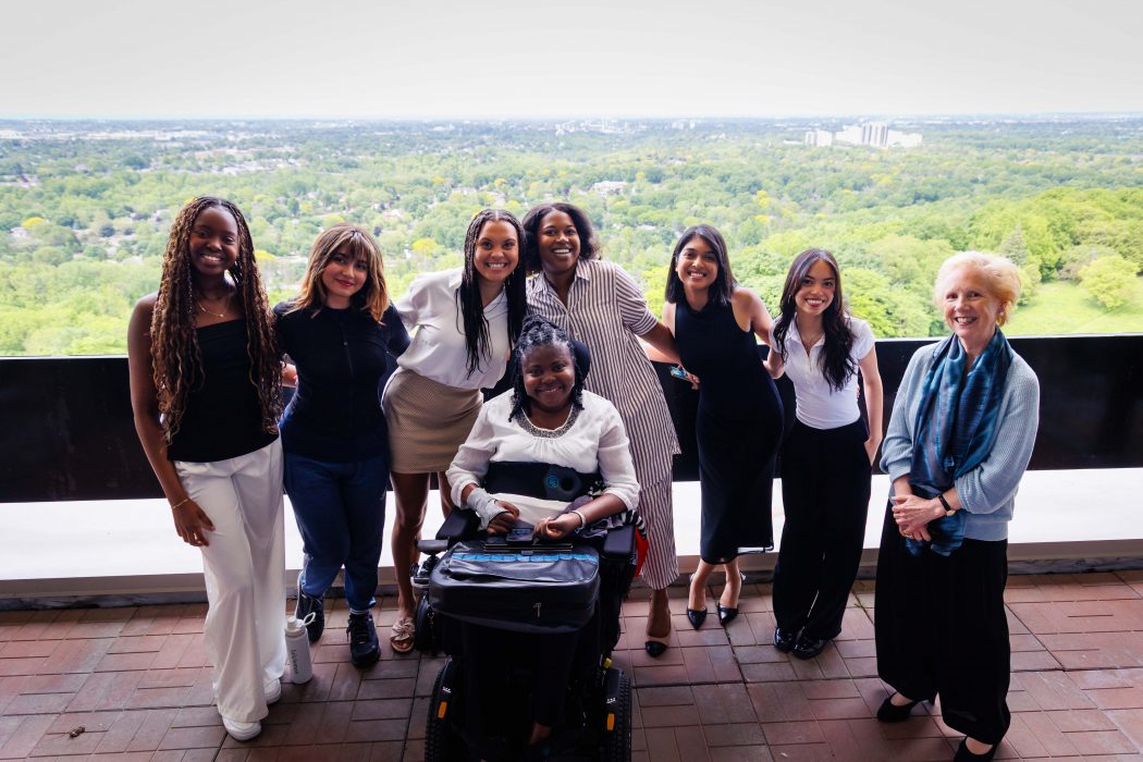 A group of women stand outside on a balcony.