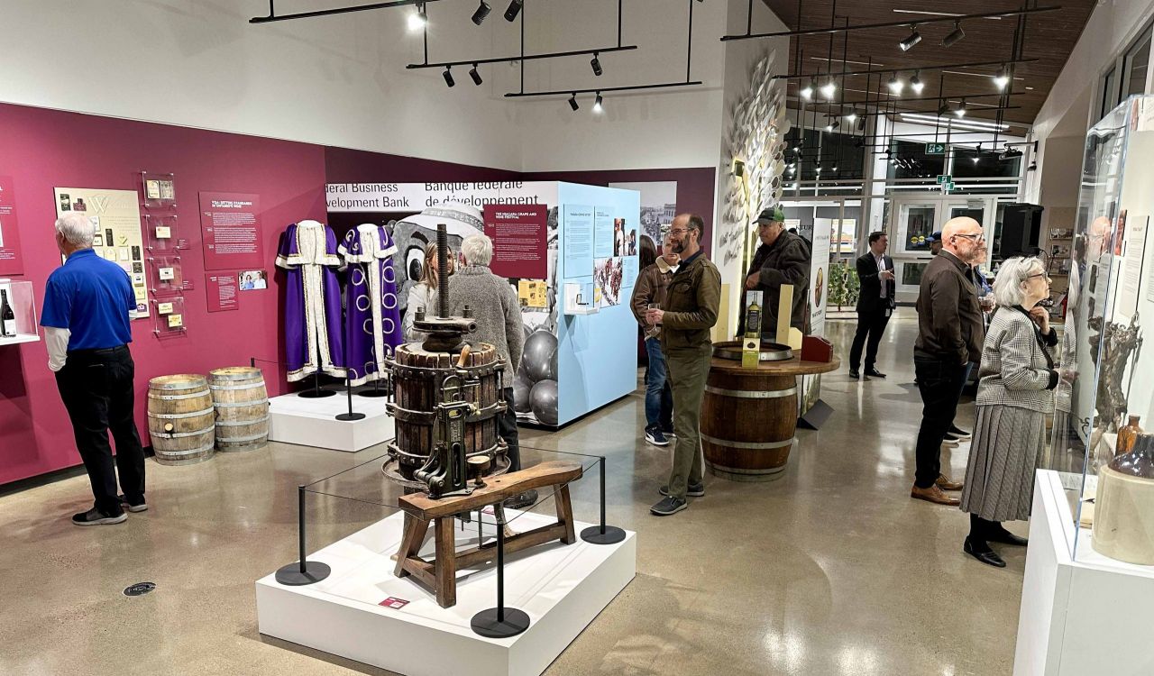 A large bright room in a museum is filled with historical images and displays depicting Niagara’s grape and wine history.