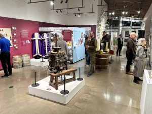 A large bright room in a museum is filled with historical images and displays depicting Niagara’s grape and wine history.