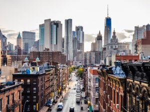 Aerial view of New York City neighbourhood with brown buildings, skyscrapers and cars on the road.