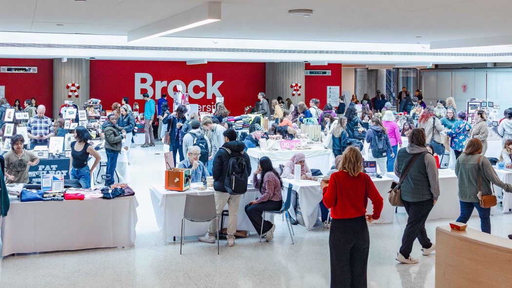 A large group of people in a holiday market in a bright event space.