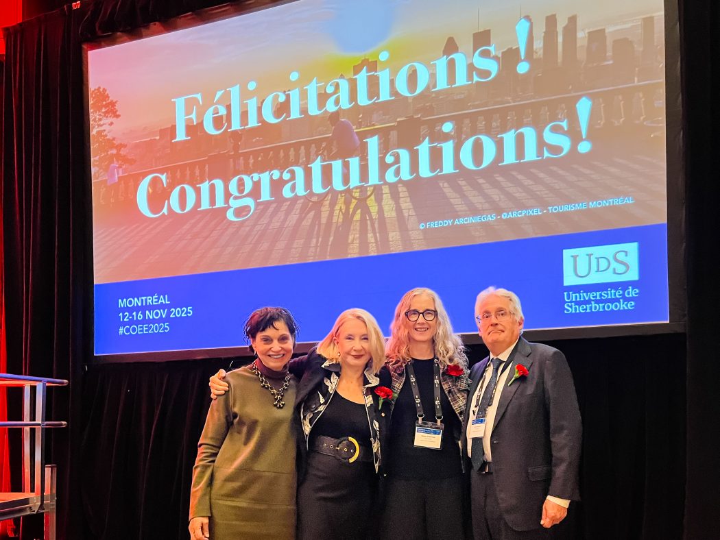 Four smiling adults stand together on a stage in front of a large screen that reads ‘Félicitations! Congratulations! at a Montréal event hosted by the Université de Sherbrooke.