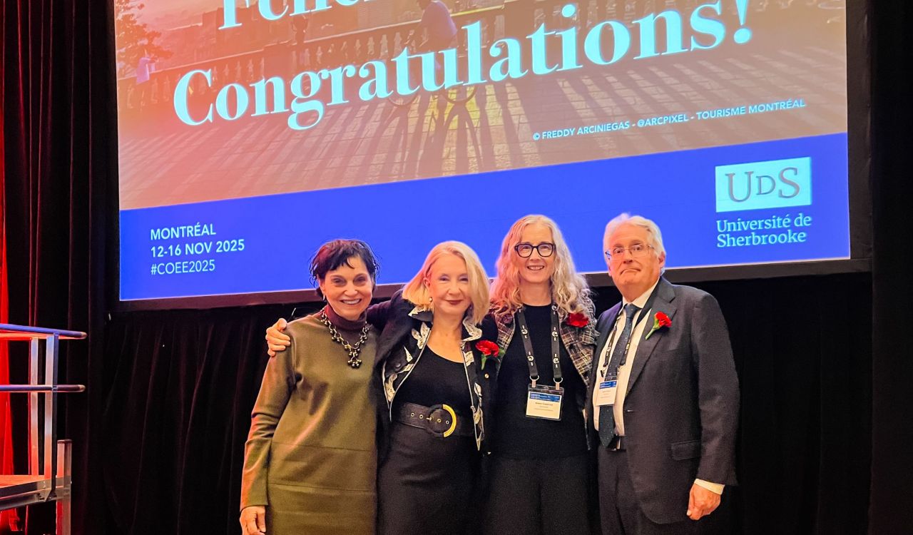 Four smiling adults stand together on a stage in front of a large screen that reads ‘Félicitations! Congratulations! at a Montréal event hosted by the Université de Sherbrooke.