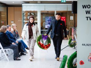 Two young people carry a wreath between them during a Remembrance Day ceremony.