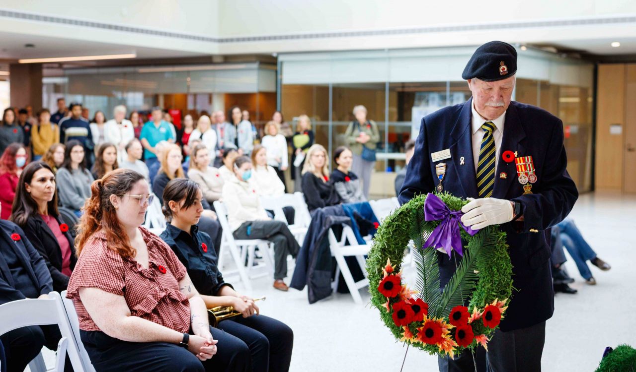 A man in a military uniform carries a wreath during a Remembrance Day ceremony.