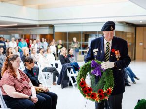 A man in a military uniform carries a wreath during a Remembrance Day ceremony.