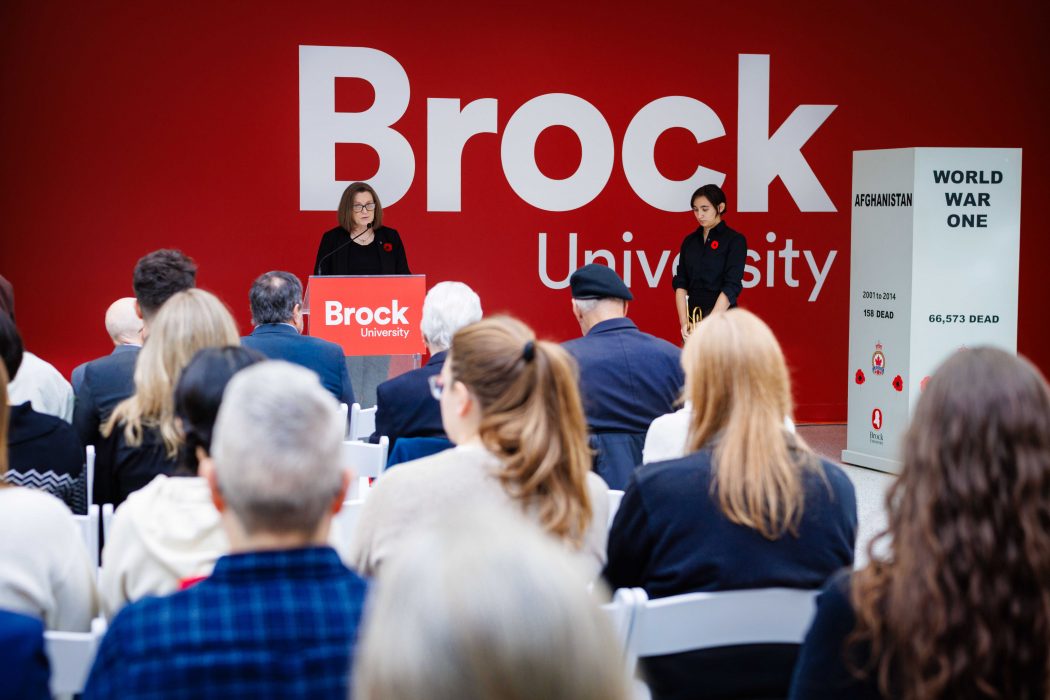 A woman speaks from a podium during a Remembrance Day ceremony.