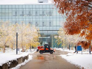 A small vehicle drives through a snowy university campus