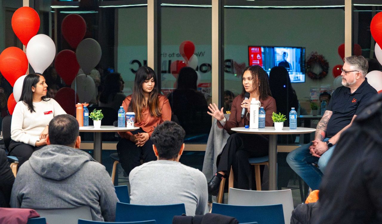 Four people sit on chairs in front of an audience.