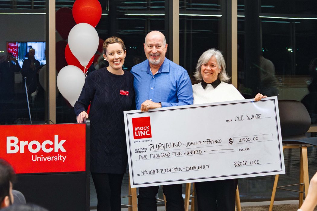 Three people pose with a giant cheque.