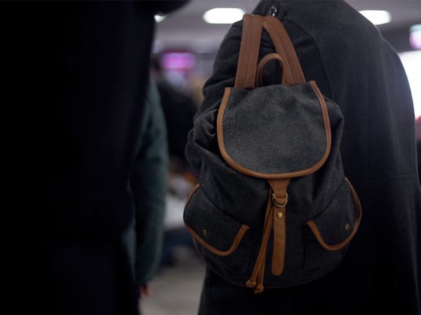 Person wearing a backpack is followed by another person in black.