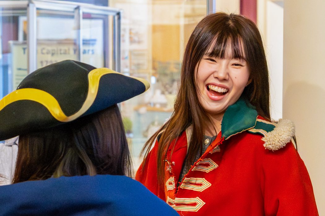 A university student tries on historical clothing at a museum.