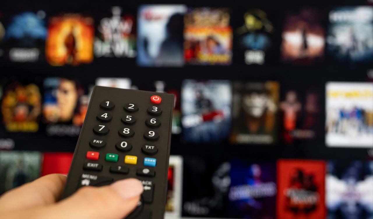 A person holds a remote while scrolling through options on a streaming service.