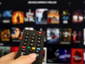 A person holds a remote while scrolling through options on a streaming service.