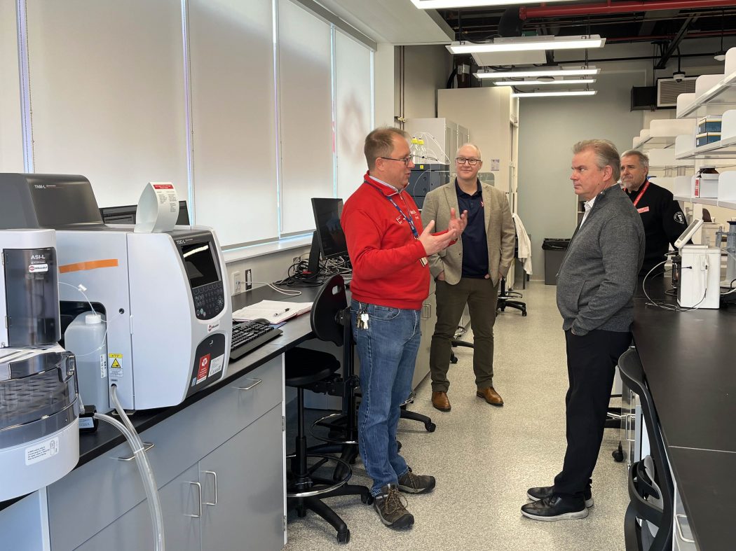 Four people stand talking in a research lab.