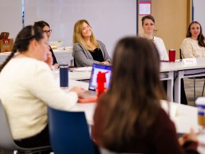 Colleagues sitting around tables have a discussion in a meeting.