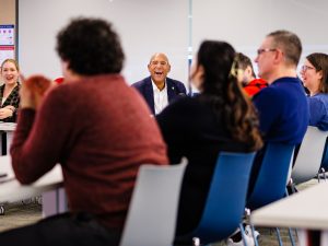 Colleagues sitting around tables have a discussion in a meeting.