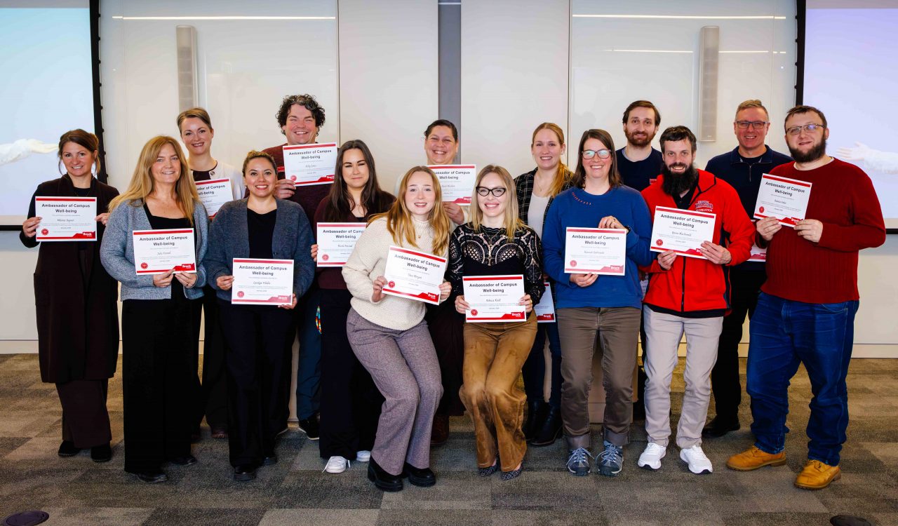 A large group of people pose for a photo while holding certificates.
