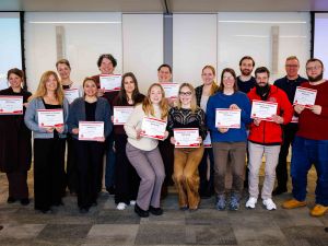 A large group of people pose for a photo while holding certificates.