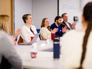 Colleagues sitting around tables have a discussion in a meeting.