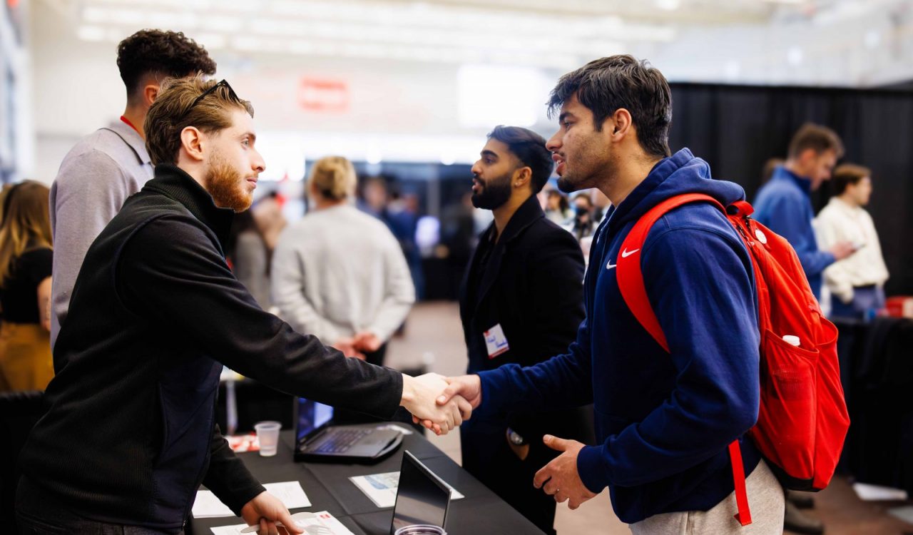 Two people have a conversation at a university job fair.