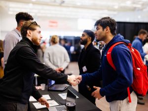 Two people have a conversation at a university job fair.