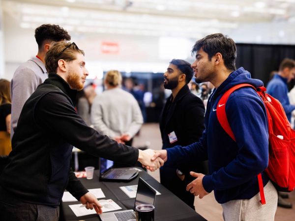 Two people have a conversation at a university job fair.