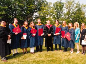 A large group of people, including students in graduation ceremony caps and gowns, posed for a picture.