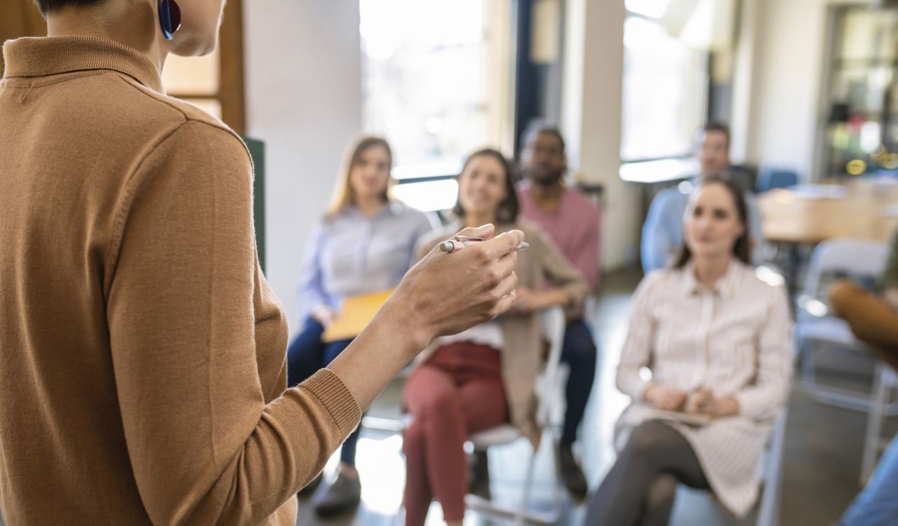 A person speaks to an audience from the front of a room.