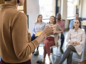A person speaks to an audience from the front of a room.