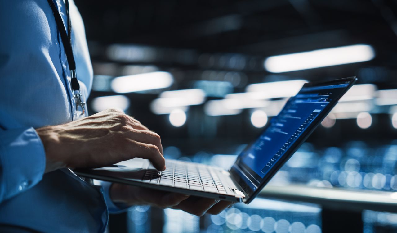 Close-up of a person typing on a laptop in a data centre.