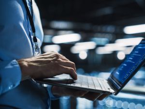 Close-up of a person typing on a laptop in a data centre.