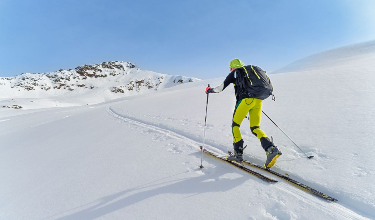 A person wearing skis ascends a snowy hill.