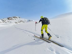 A person wearing skis ascends a snowy hill.