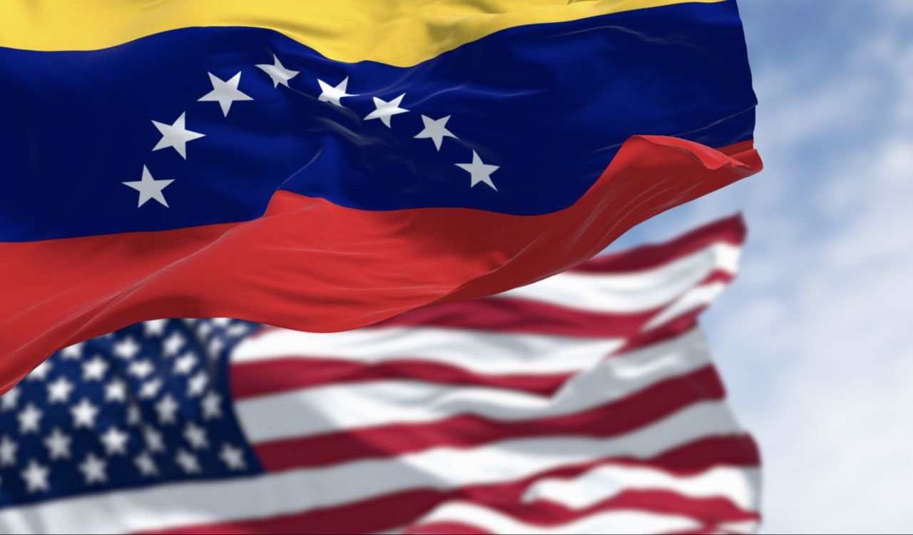 Venezuela and US national flags waving in the wind on a clear day.