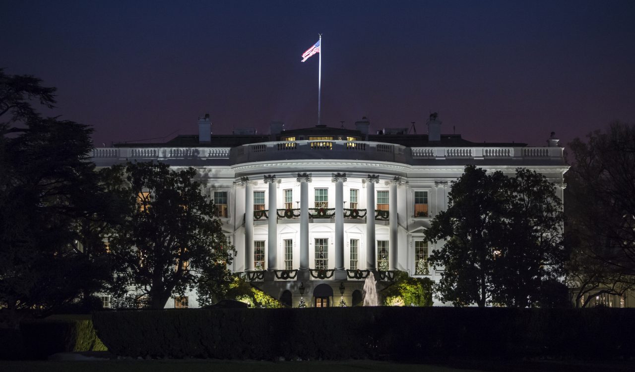 The White House at night with lights glowing from the building.