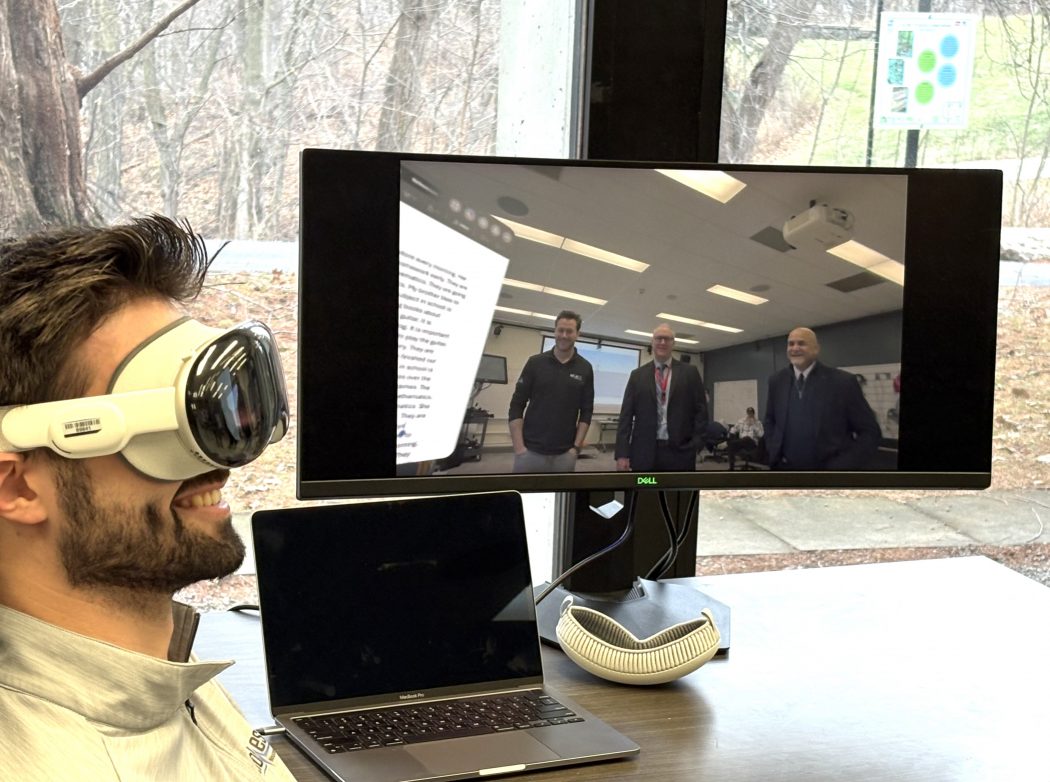 A person wearing goggles in front of a screen.