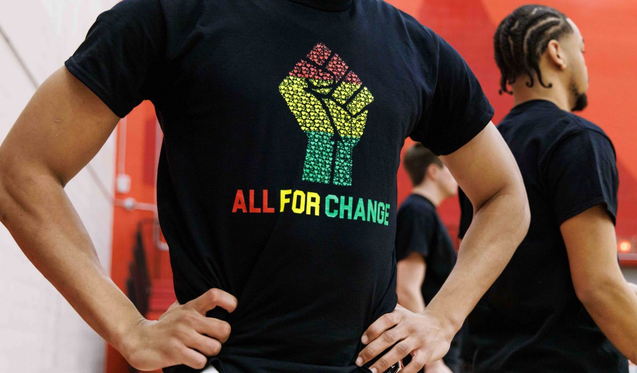 Close-up of a person wearing a t-shirt with an All for Change logo on it.