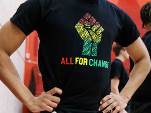 Close-up of a person wearing a t-shirt with an All for Change logo on it.