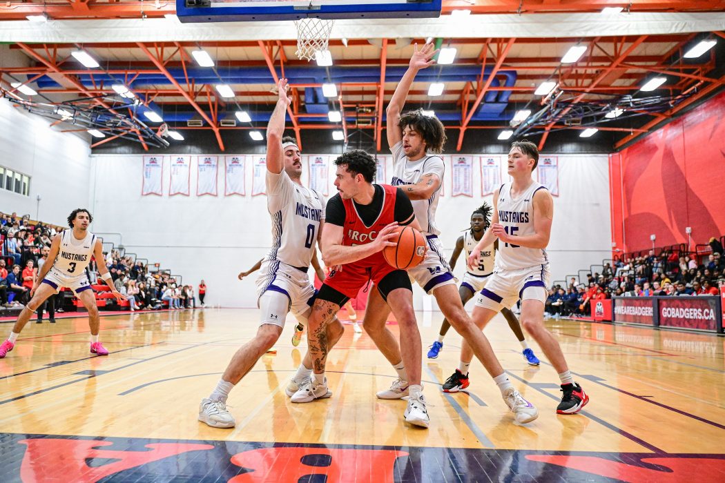 Four university students play basketball.