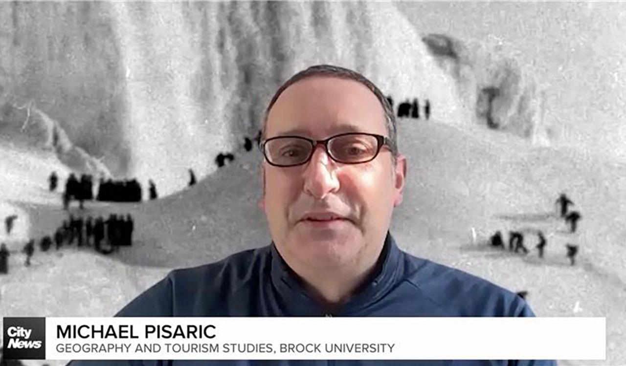 A man speaks on the news with a snowy photo in the background.