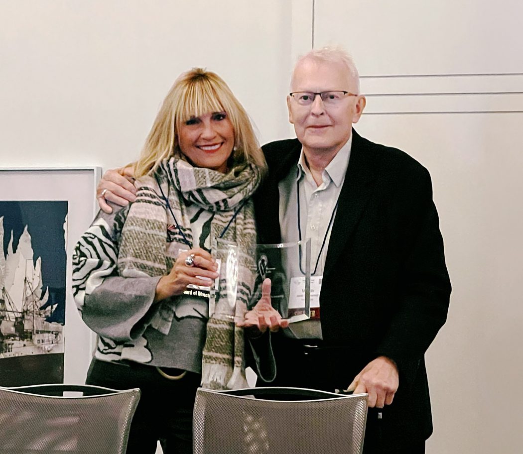 Dr. Andrea McKee (left) holds a transparent plaque in both hands with Martin Tammemägi (right) standing next to her.