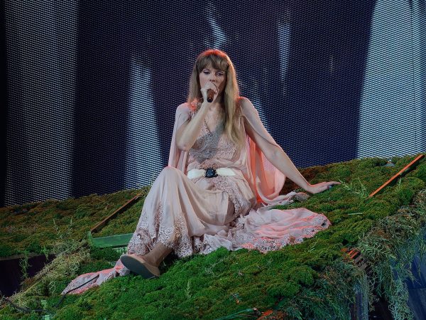Taylor Swift sits on stage and sings.
